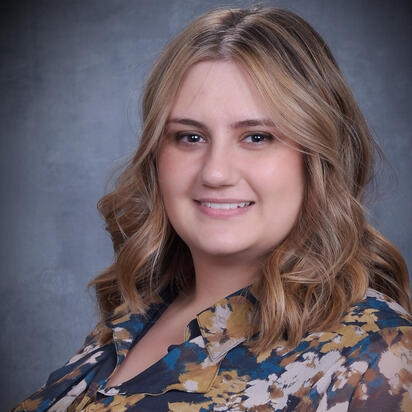 Portrait of a white, feminine-presenting person smiling at the camera